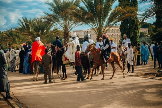 Vibrant cultural parade with people in traditional attire riding horses outdoors.