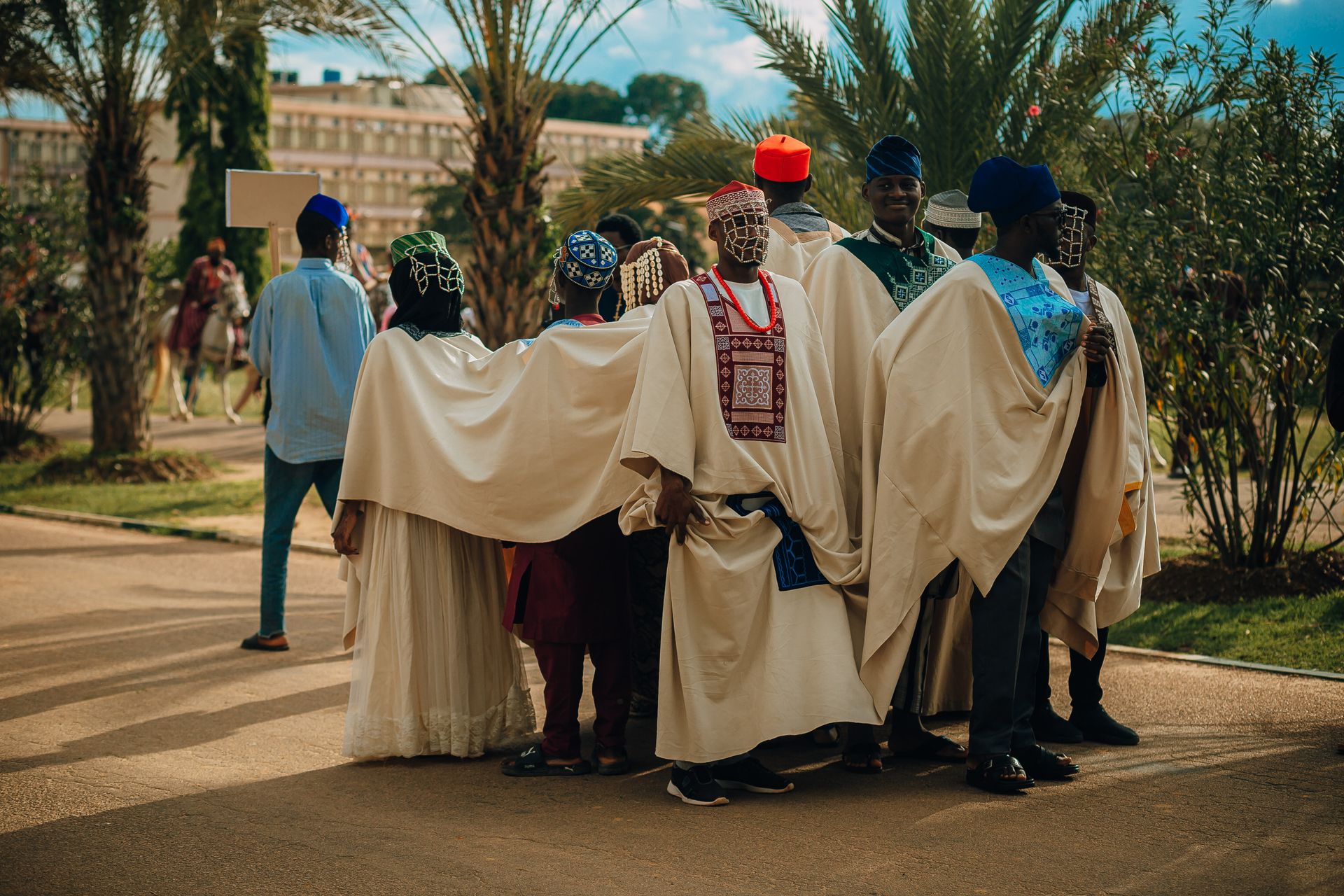 Group of people in traditional African attire standing together in a garden setting.
