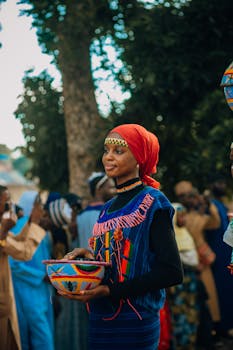 Woman in festive attire holding a colorful basket at a cultural celebration outdoors.