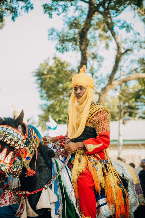Free Man in traditional costume riding a decorated horse at an outdoor festival, embodying cultural heritage. Stock Photo
