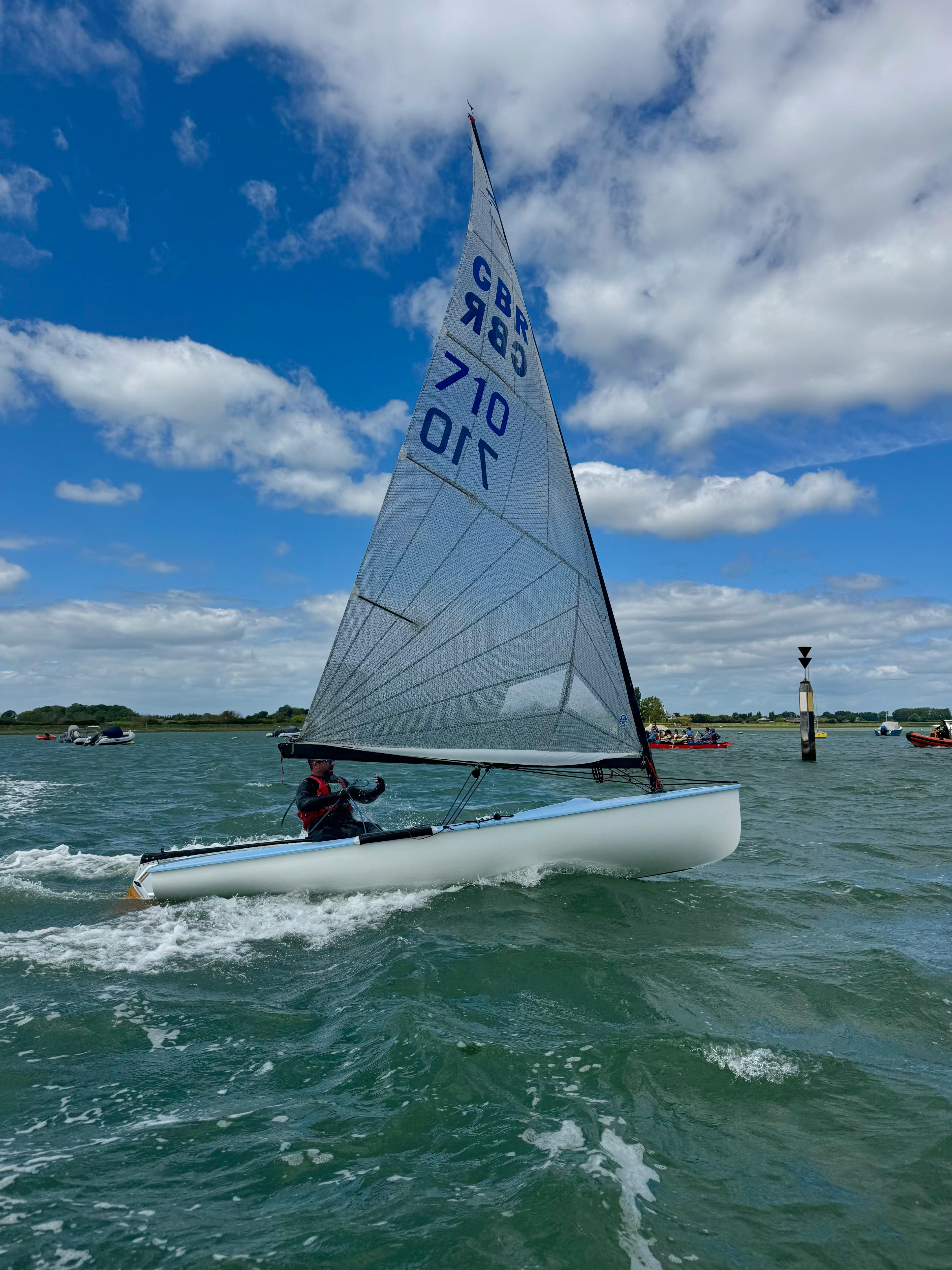 Sailboat with a person enjoying a sunny day on the sea under blue skies.