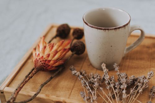 Free A cozy scene featuring a rustic mug paired with dried flowers on a wooden tray. Stock Photo