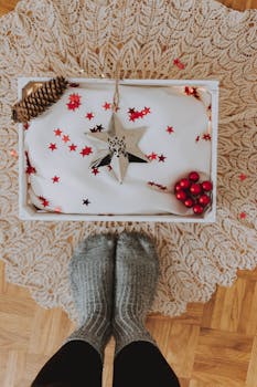 木地板上装饰着圣诞礼品盒，配有舒适的羊毛袜子