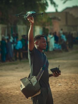 Man controlling a drone with a remote in an outdoor setting, showcasing modern technology.