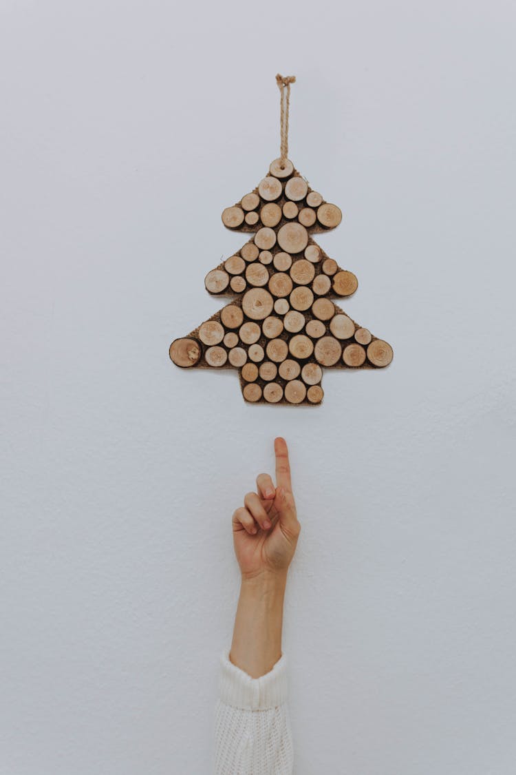 Unrecognizable Person Demonstrating Christmas Decoration Hanging On Wall