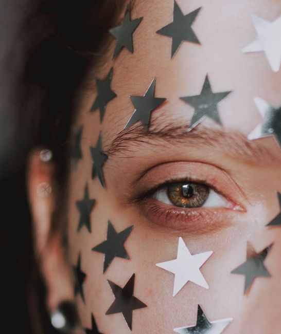 Artistic close-up portrait of a woman with star stickers on her face, creating a unique fashion statement.