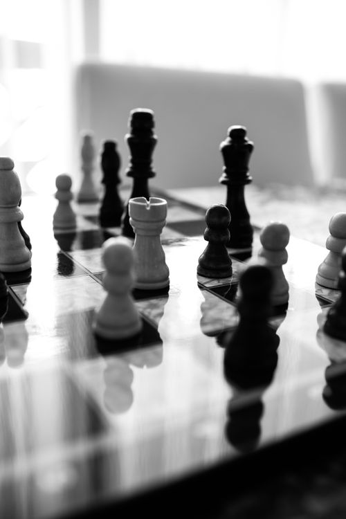 Free Monochrome chess pieces on a reflective board indoors, highlighting strategy and elegance. Stock Photo
