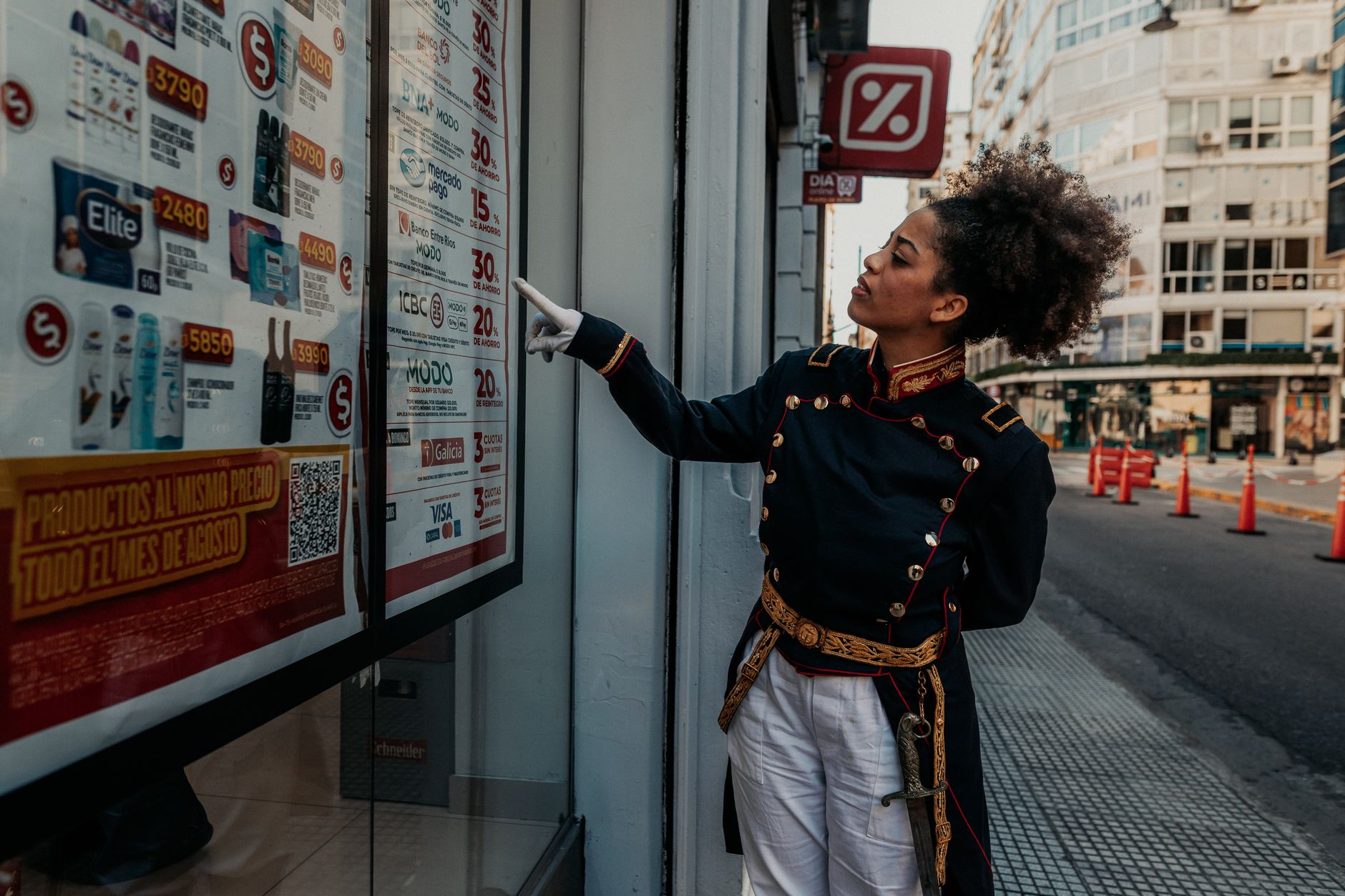 An individual dressed in historical clothing interacts with a store window display in Buenos Aires, Argentina.