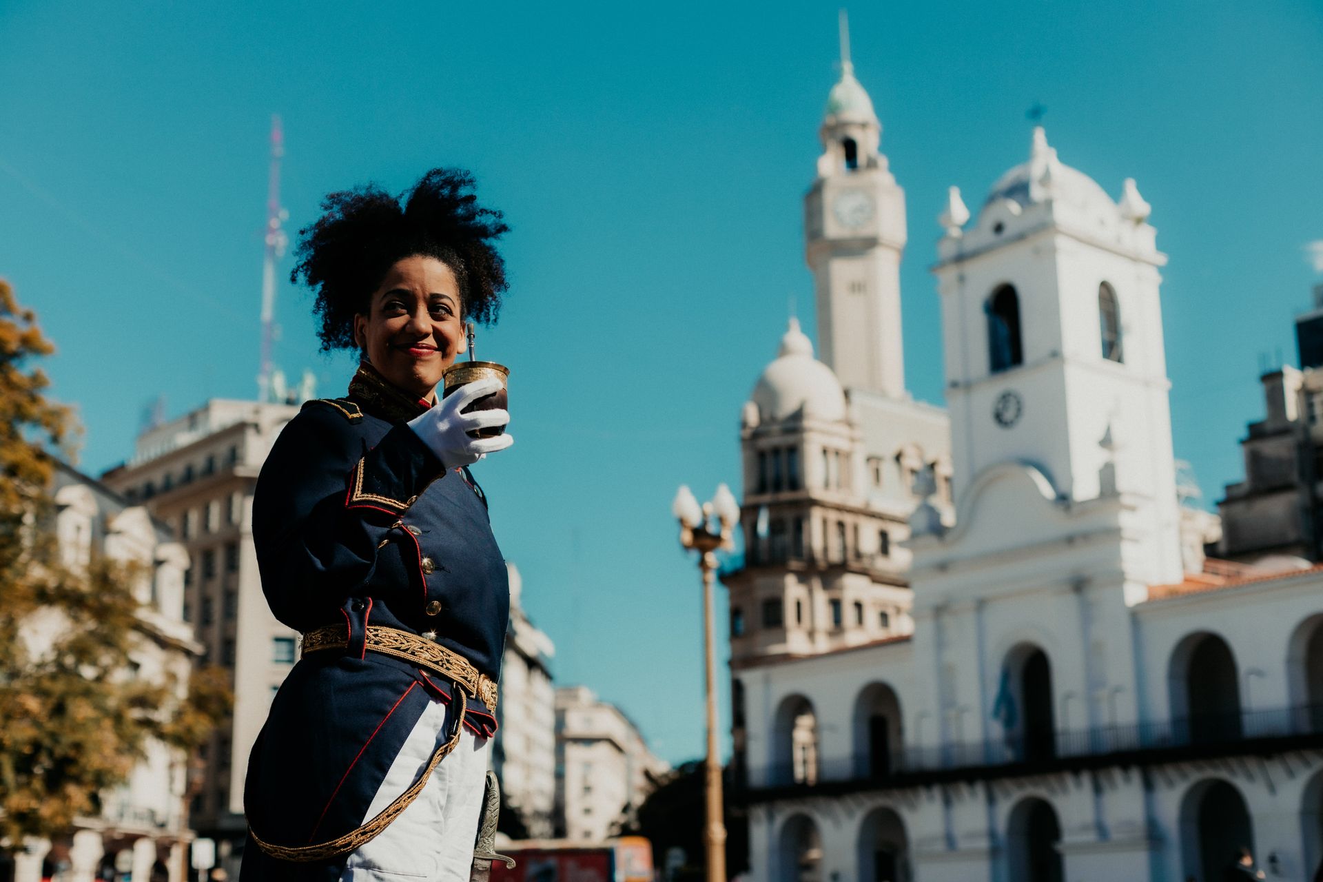 Performer in traditional attire at Buenos Aires' historic Plaza de Mayo under a bright blue sky.
