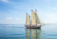 一艘帆船风景如画，人们在晴朗的天空下享受海上的一天