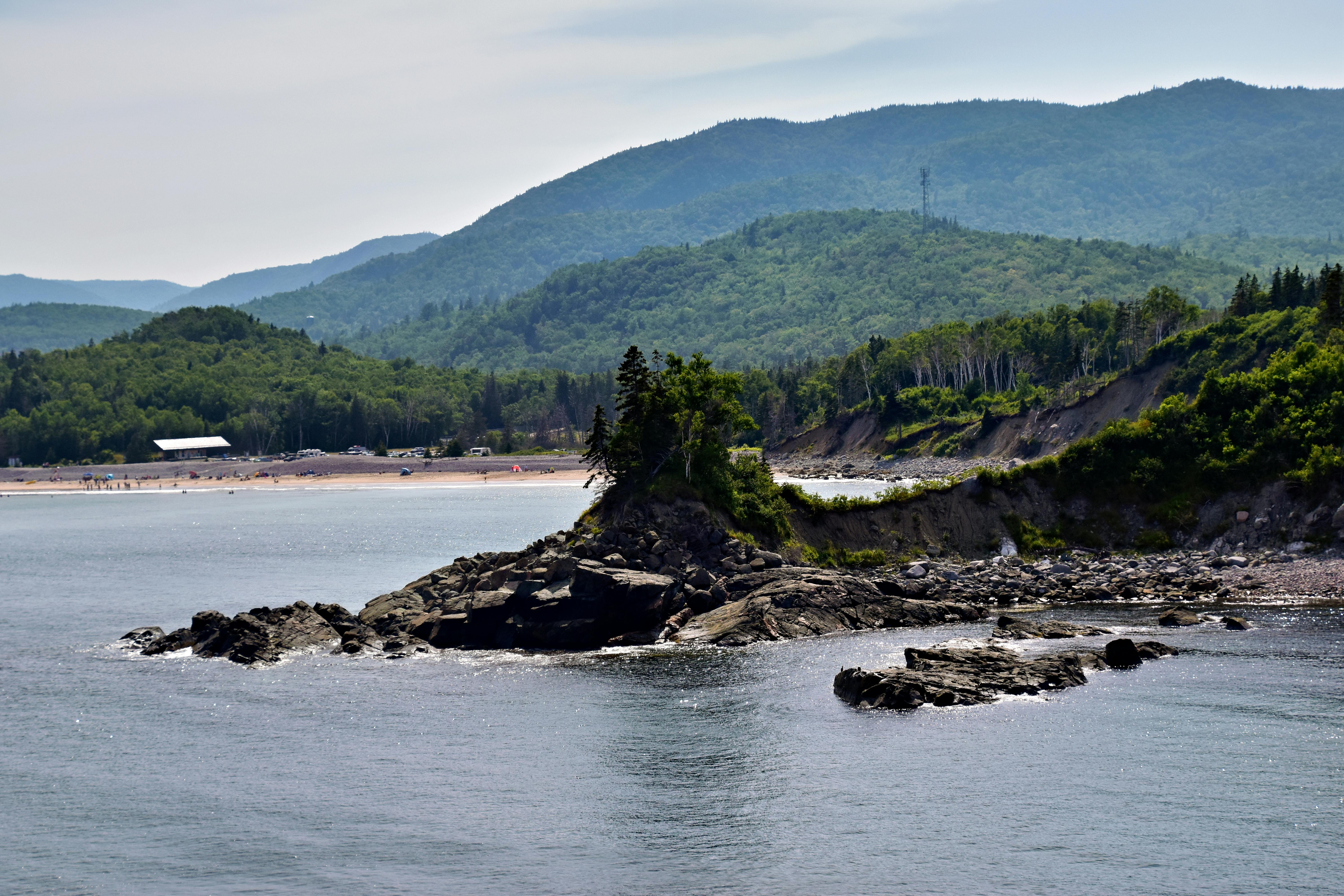 Beautiful coastal landscape with rocky shoreline and lush green hills in Nova Scotia, Canada.