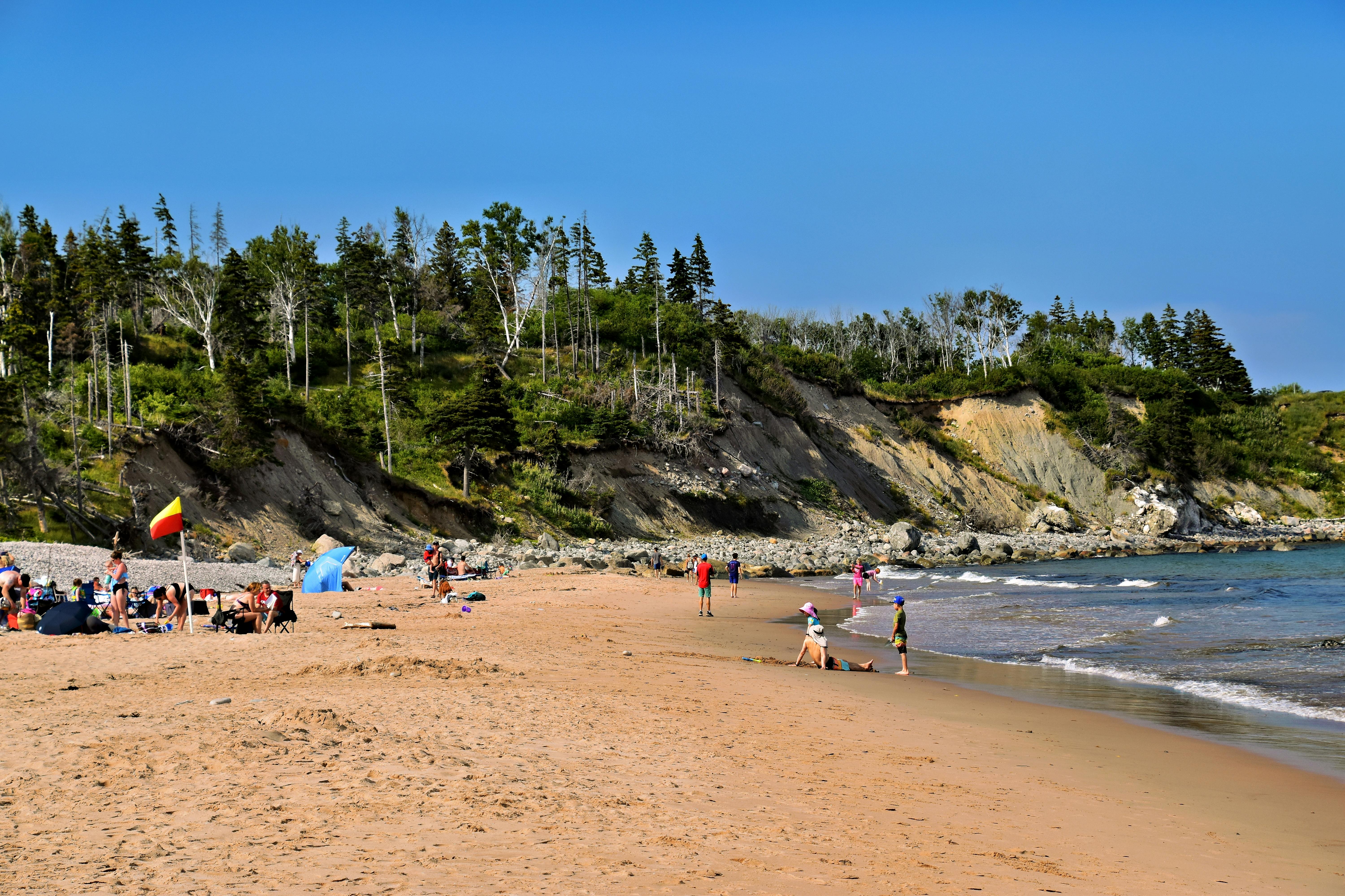 Tourists enjoy the beach under clear skies in Nova Scotia, Canada.