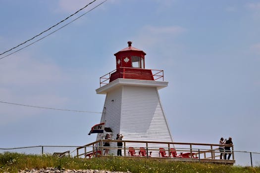 A picturesque lighthouse with Canadian flag in Nova Scotia, a popular tourist attraction.