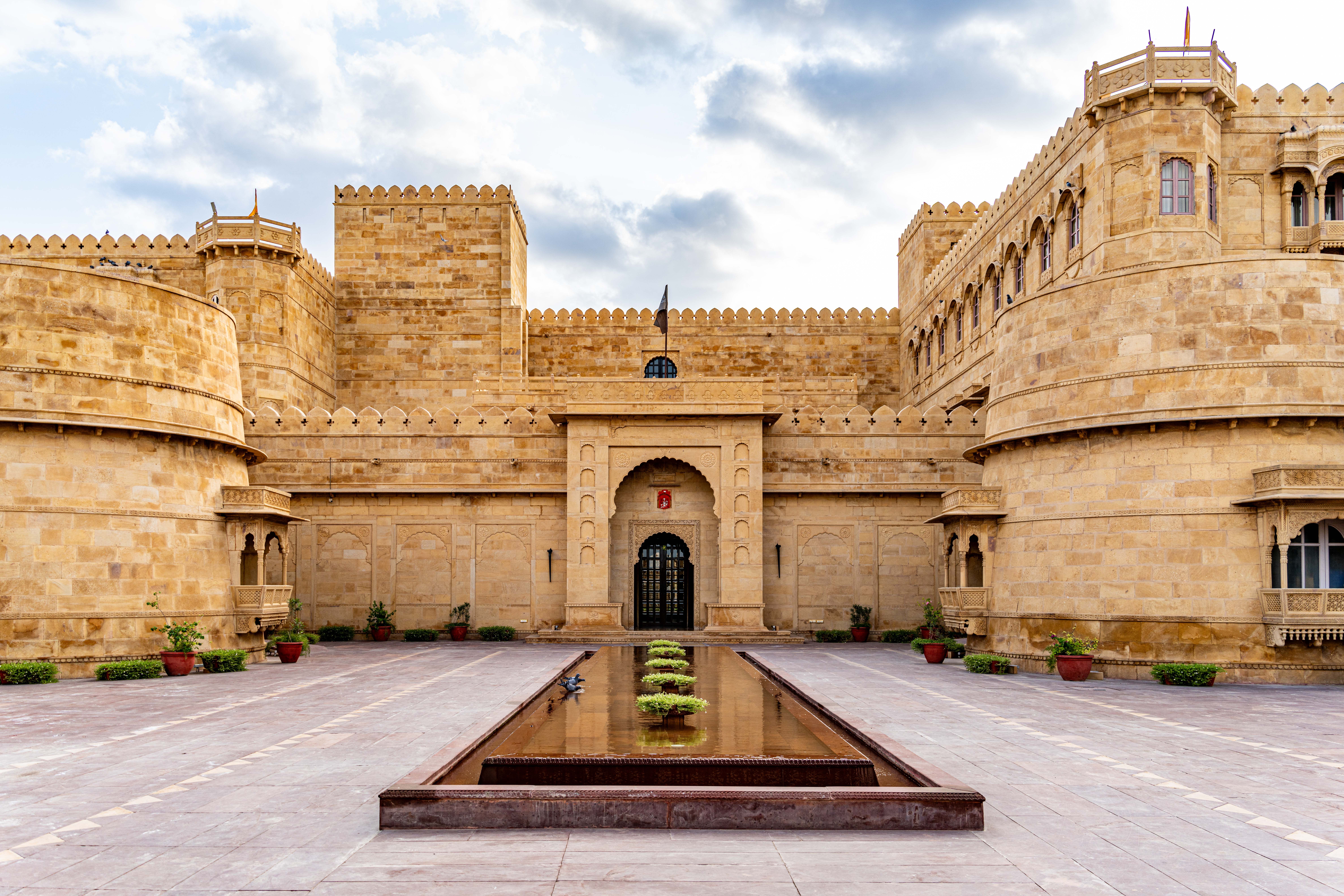 Majestic cream sandstone facade of a Rajput heritage property with domed chhatris and carved jharokha windows