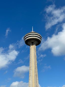 Iconic Skylon Tower in Niagara Falls viewed against a vibrant blue sky with clouds.