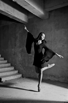 Black and white photo of a ballet dancer performing gracefully in an industrial environment.