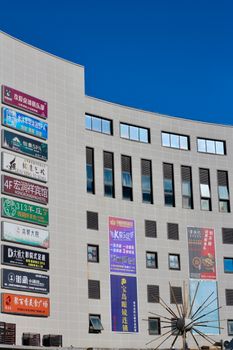 Exterior view of a commercial building featuring multiple colorful advertisement signs under a clear blue sky.