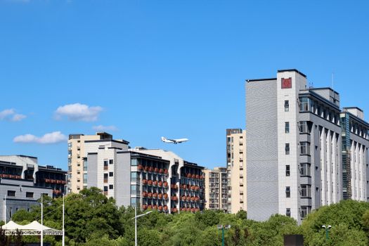 Cityscape featuring modern buildings with airplane flying overhead on a clear sunny day.