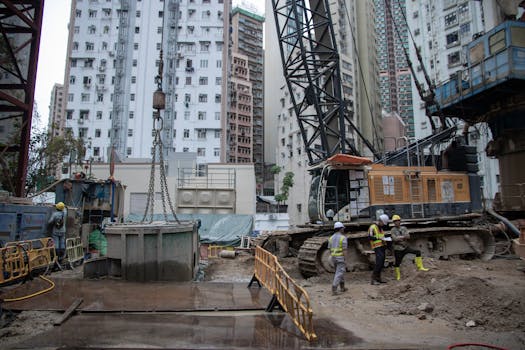 City construction site with workers, cranes, and high-rise buildings.