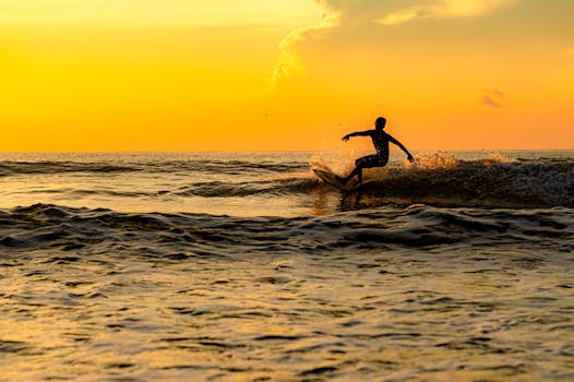 A silhouette of a surfer riding waves at sunset in Malita, Davao Region, Philippines.
