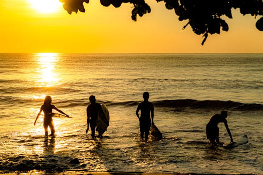 Silhouetted surfers enjoy the sunrise on a beach in Malita, Philippines.