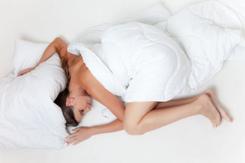 躺在白色的纺织触摸白色枕头上的女人