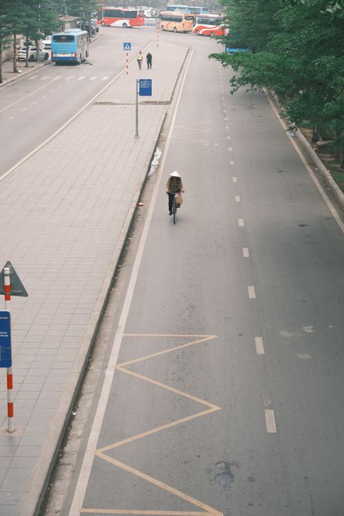 Free A lone cyclist rides along an empty road in Hà Nội, Vietnam, creating a sense of solitude. Stock Photo