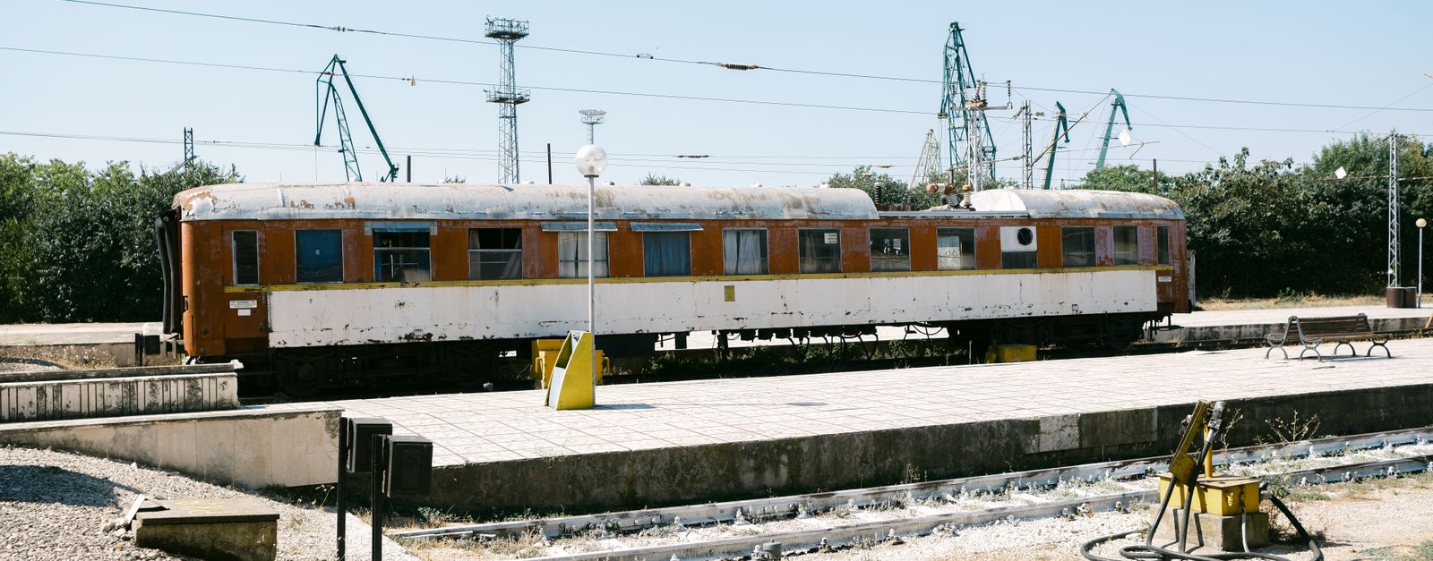 Rustic train car at an outdoor station in Varna, Bulgaria under a clear summer sky.