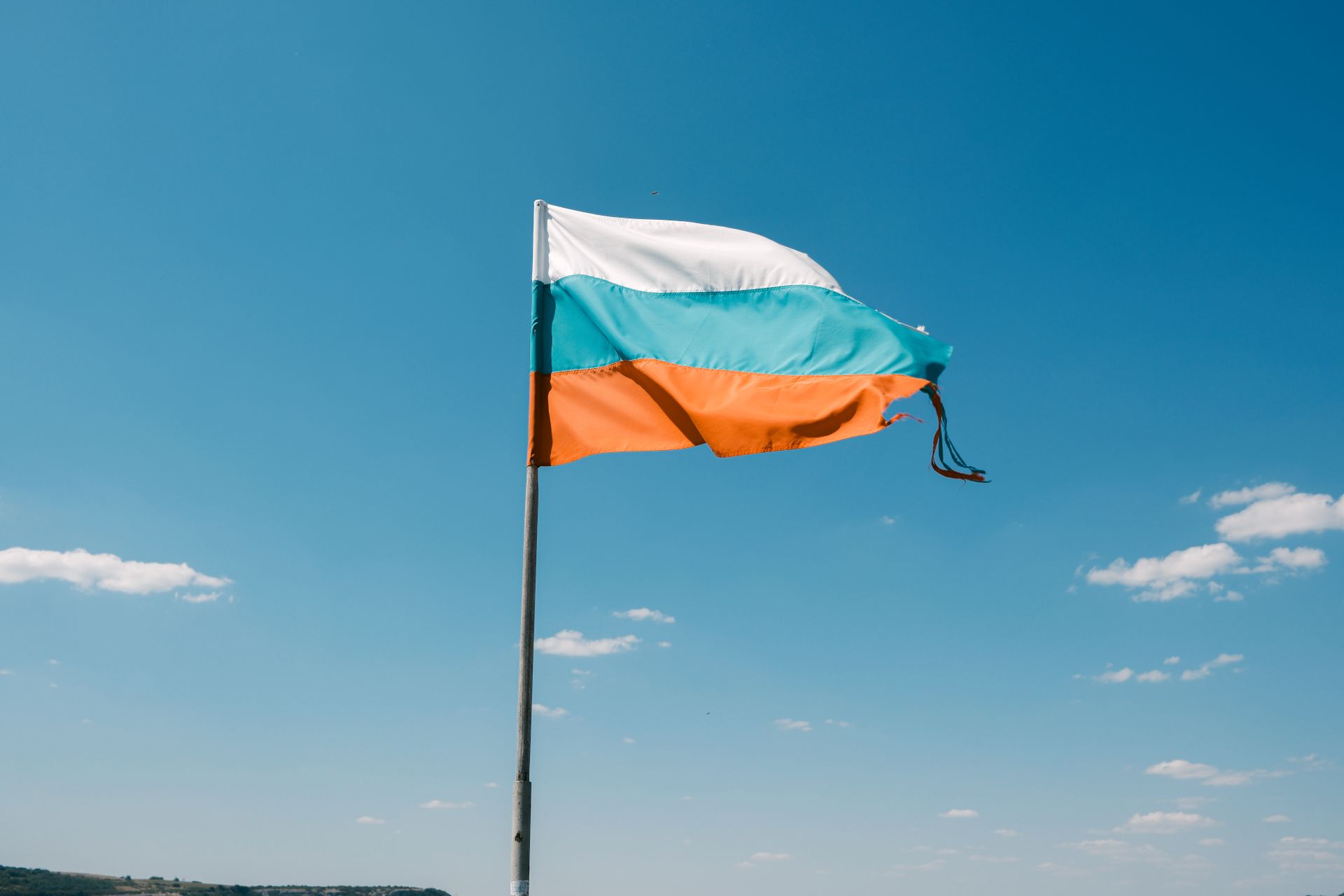 Vibrant Bulgarian flag waving under a clear blue sky in Varna, Bulgaria.