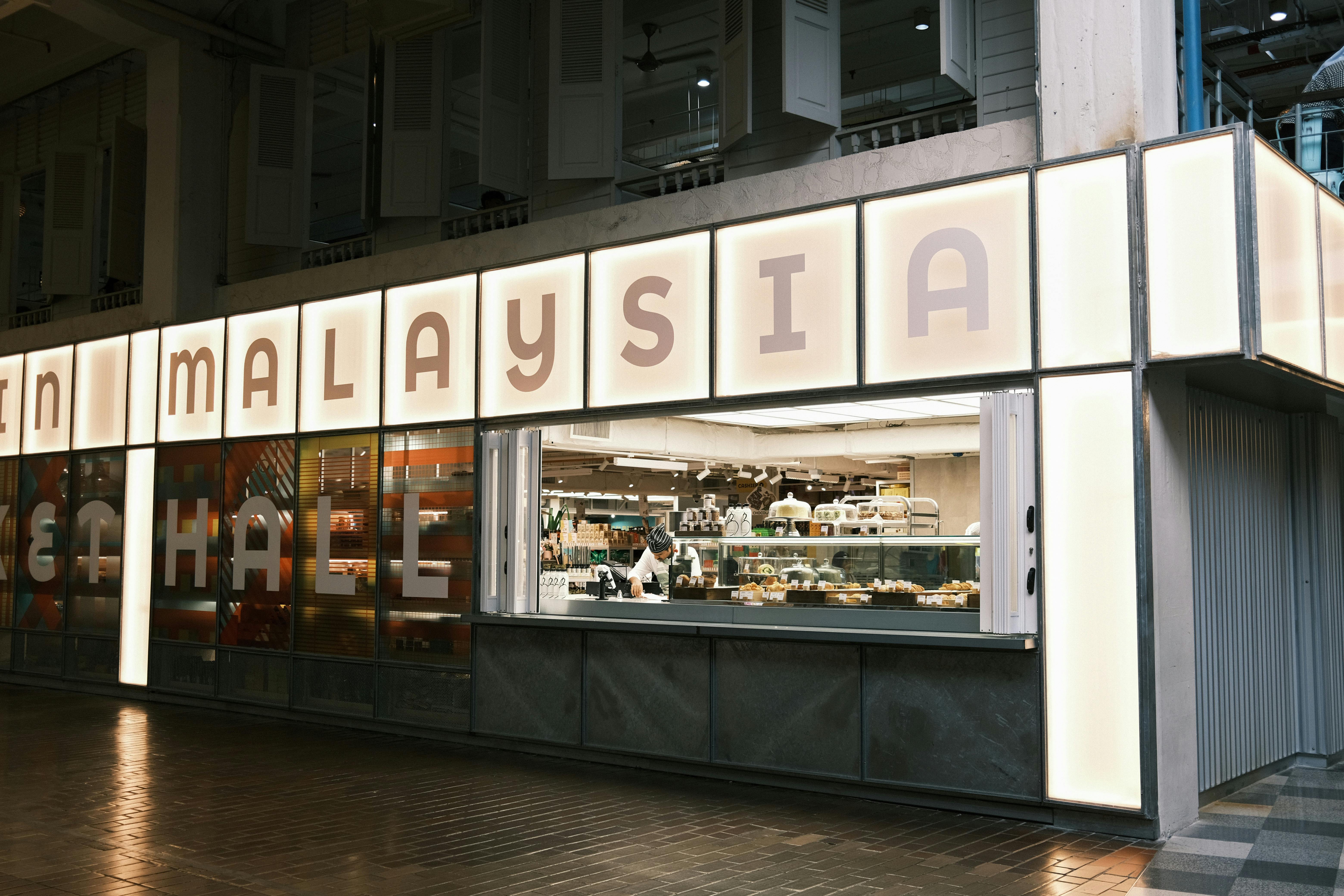 Chef preparing food in a modern urban food hall in Malaysia.
