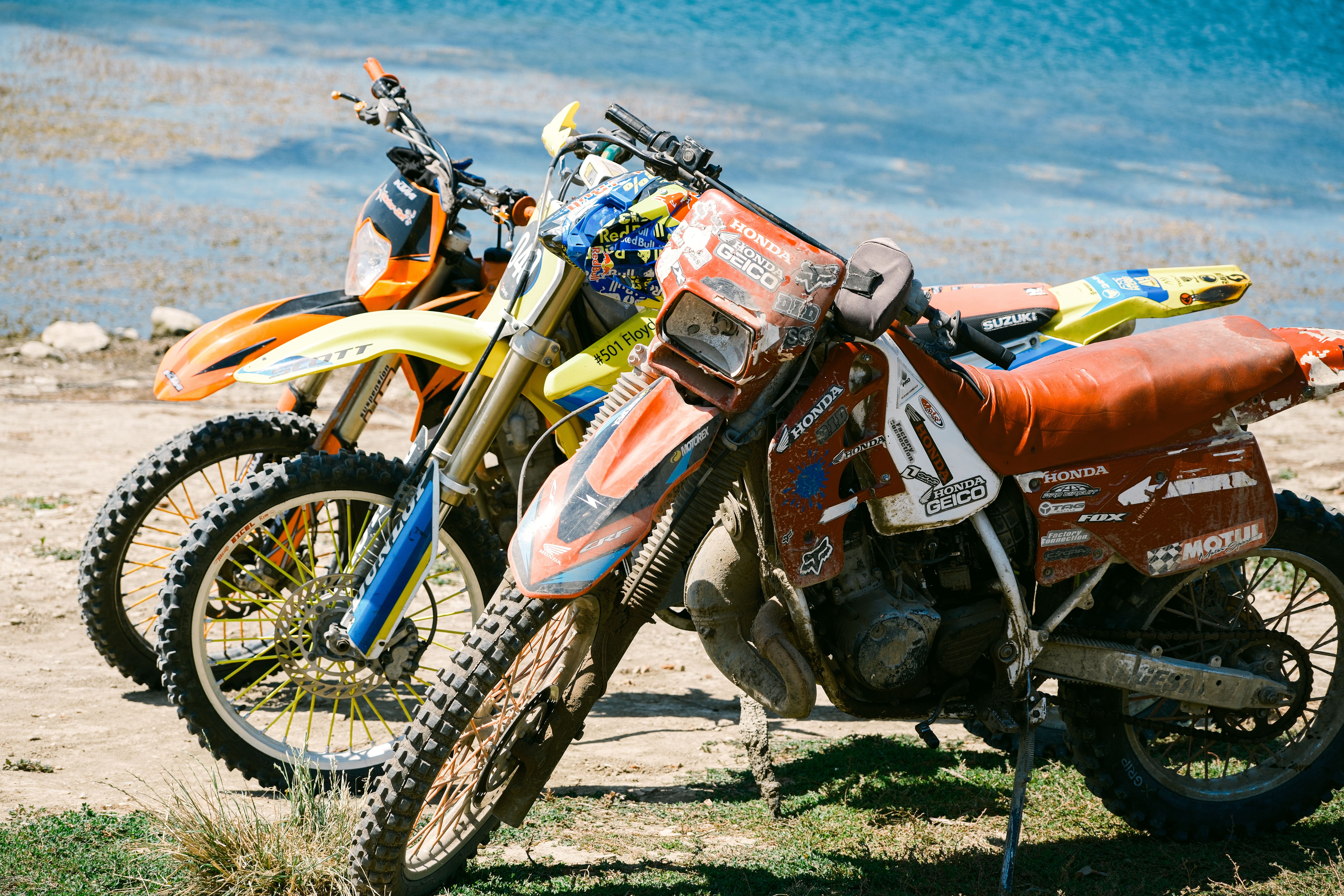 Three dirt bikes parked by the scenic sea in Varna, Bulgaria, on a sunny day.