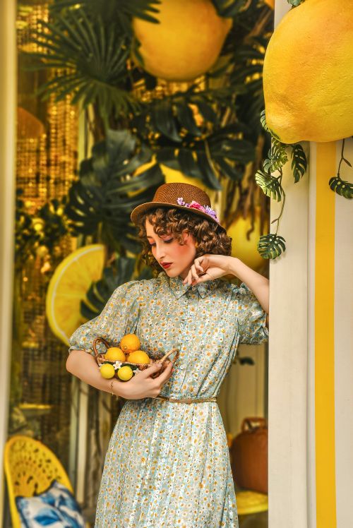 Free Stylish woman poses indoors with a basket of lemons, embraced by vibrant, tropical decor. Stock Photo