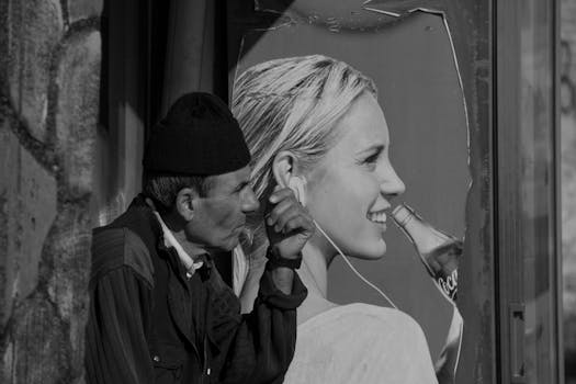 A black and white street scene showing a man next to a vibrant billboard with contrasting visuals.
