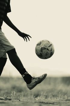 Silhouette of a young boy playing soccer in Kampala, Uganda, highlighting street sports culture.