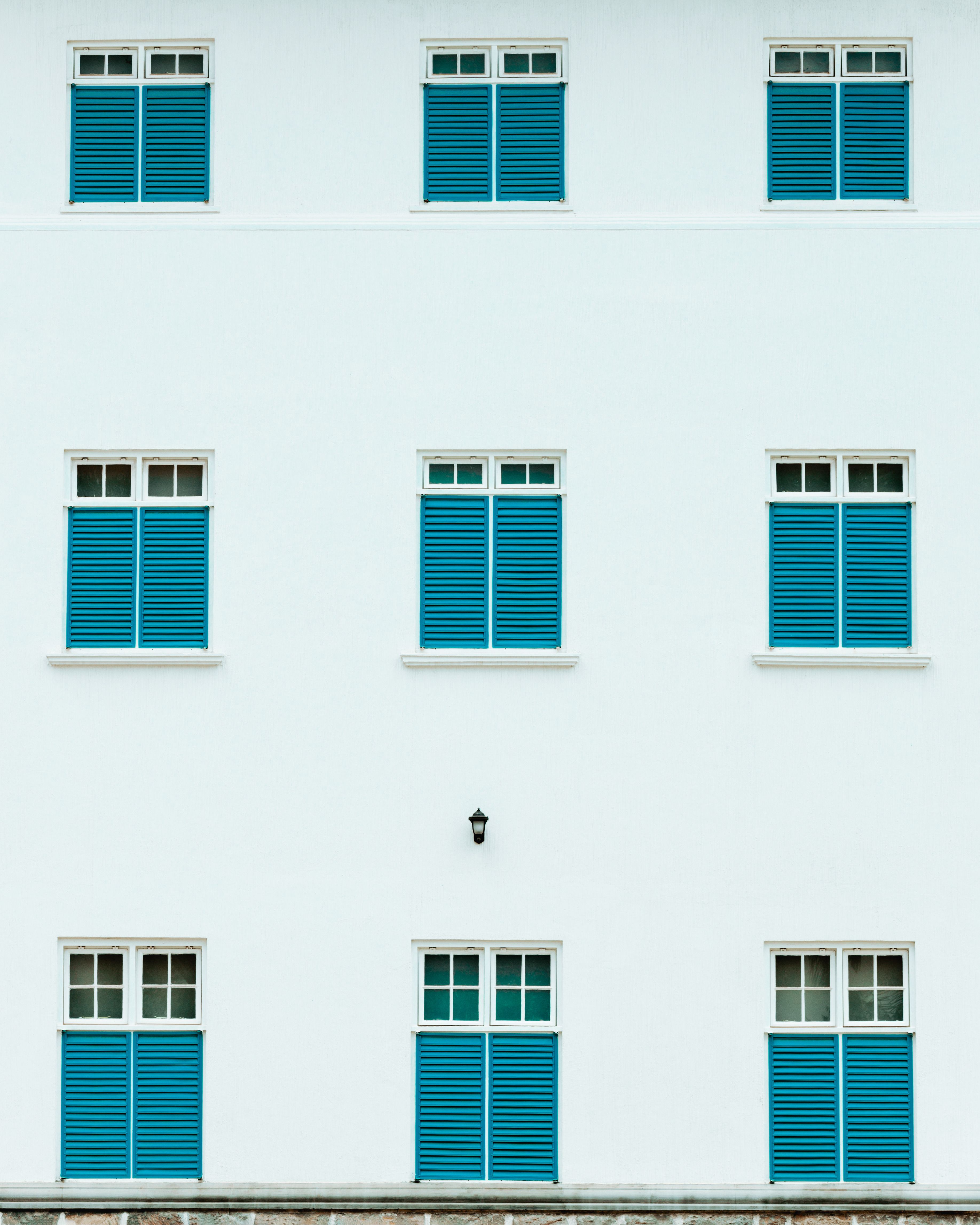 Simple white building facade with blue shutters, creating a clean and modern look.