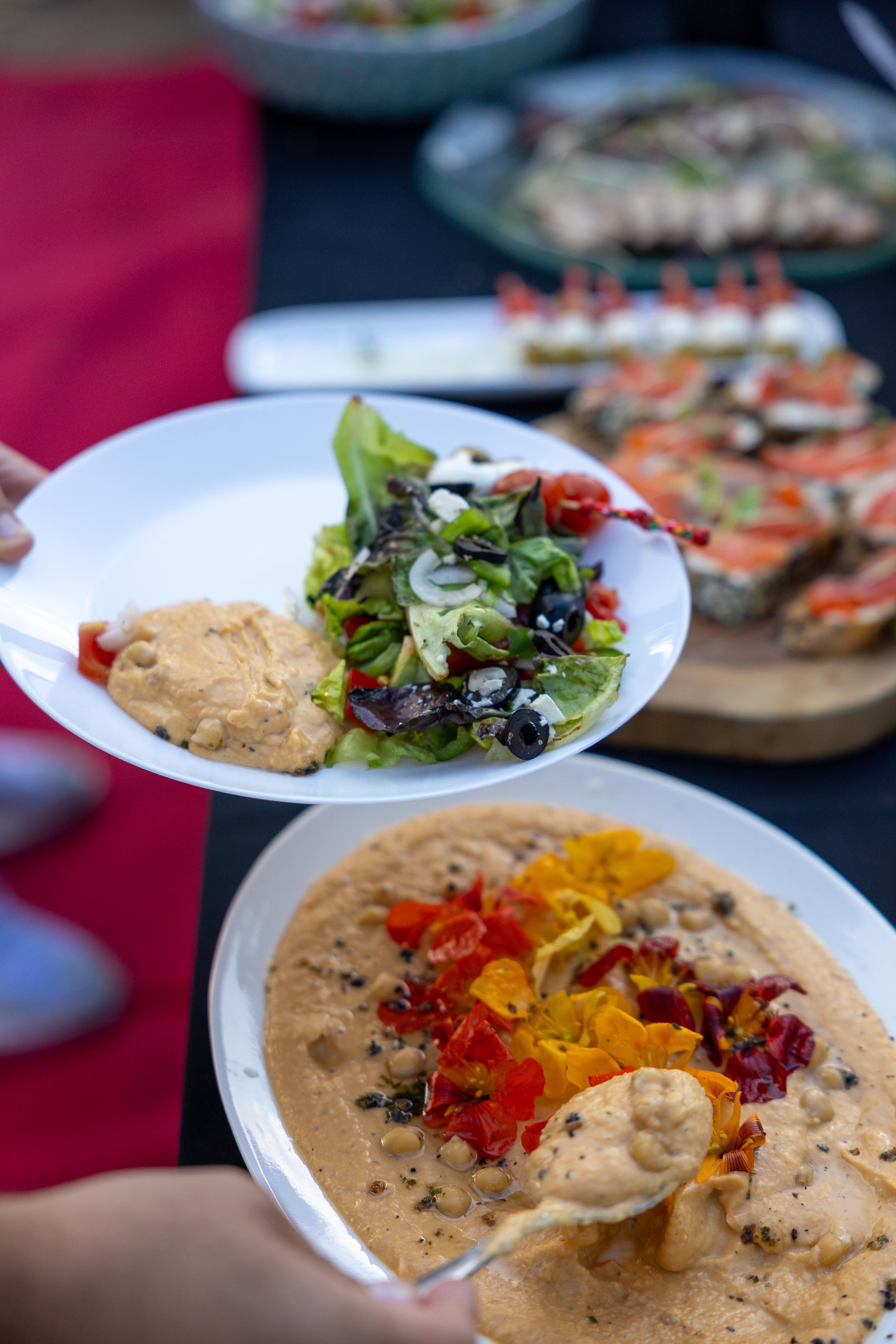 Colorful buffet display featuring fresh salad and hummus, ideal for a healthy meal setting.