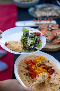 Colorful buffet display featuring fresh salad and hummus, ideal for a healthy meal setting.