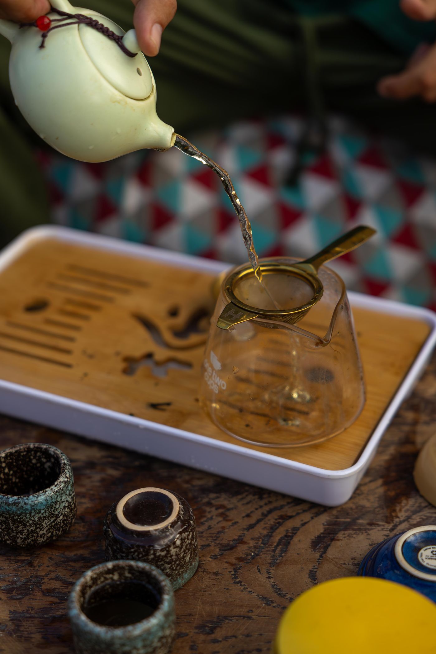 Tea being poured from a teapot into a glass cup.