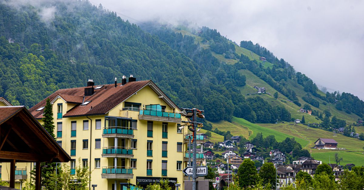 Charming mountain town with residential buildings and lush greenery on a cloudy day.