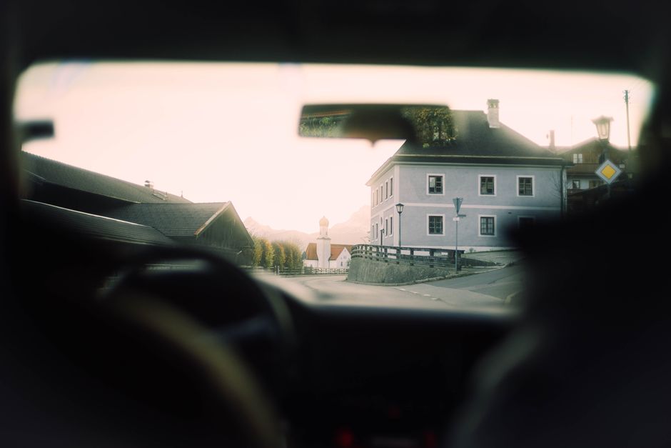 View from a car's interior, showcasing a charming European village during a peaceful daylight drive.