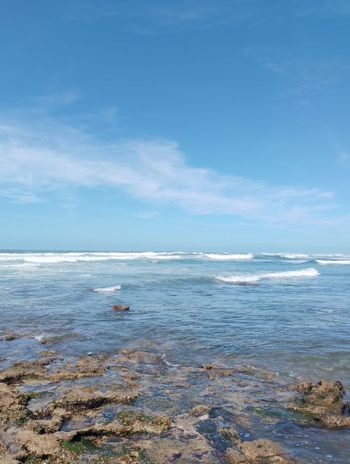 Free Tranquil coastal scene in Casablanca, Morocco capturing waves breaking on rocky shores under a clear blue sky. Stock Photo