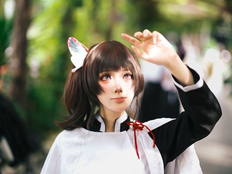 A young adult in anime-inspired Japanese cosplay outfit, outdoors with nature background.