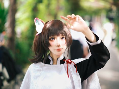 Vibrant portrait of a cosplay enthusiast with butterfly accessory in a lush outdoor setting.