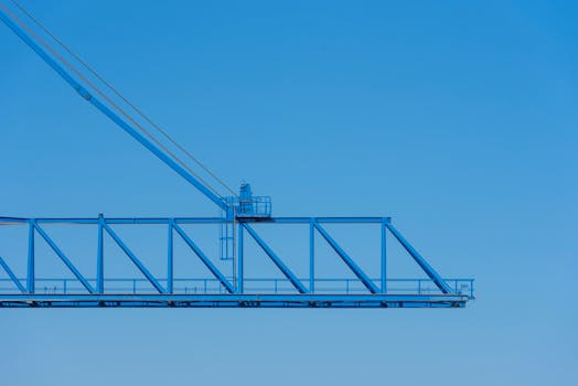 A blue construction crane extends against a clear blue sky, highlighting industrial strength.