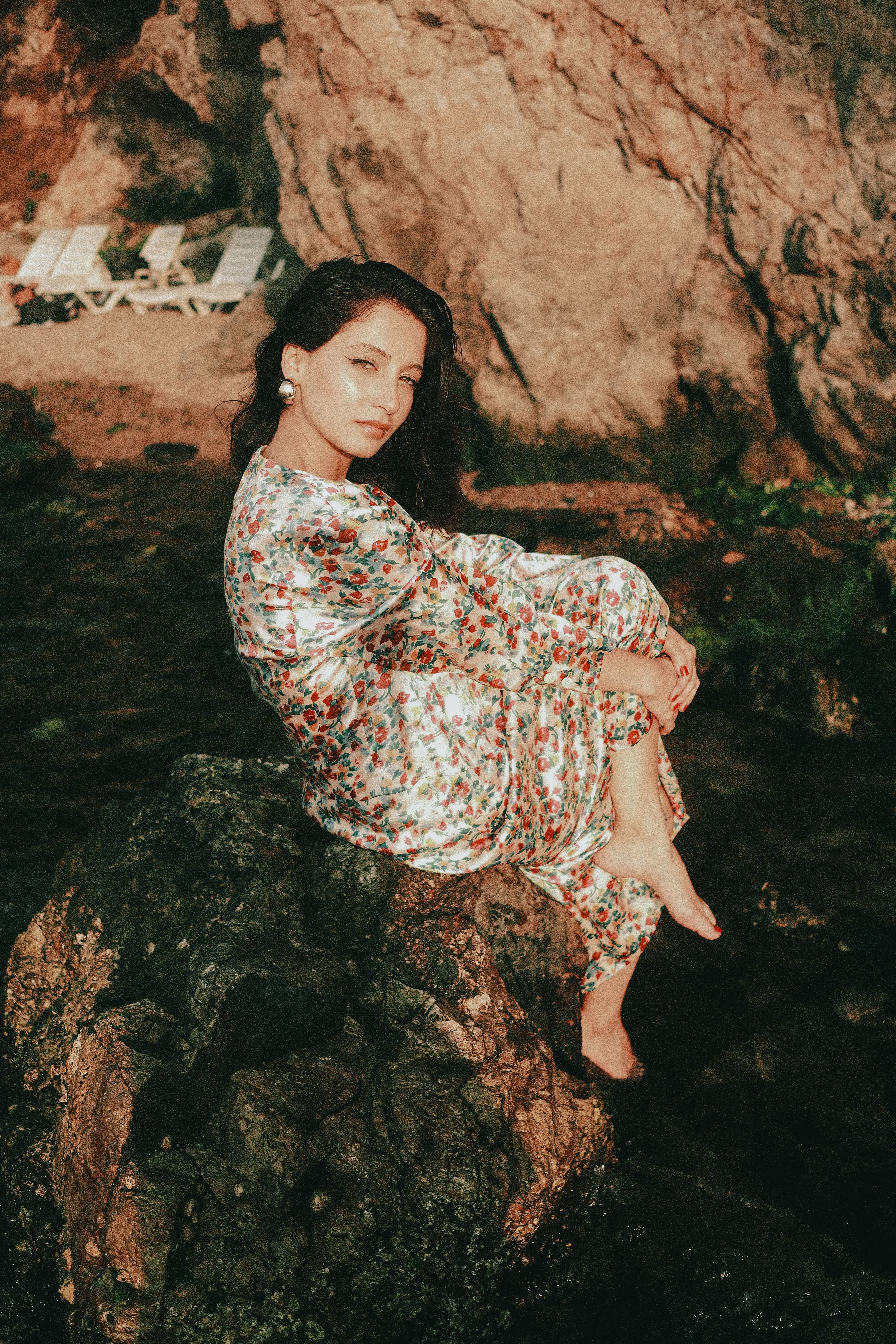 Woman in Floral Dress Sitting on Rocks by the Sea · Free Stock Photo
