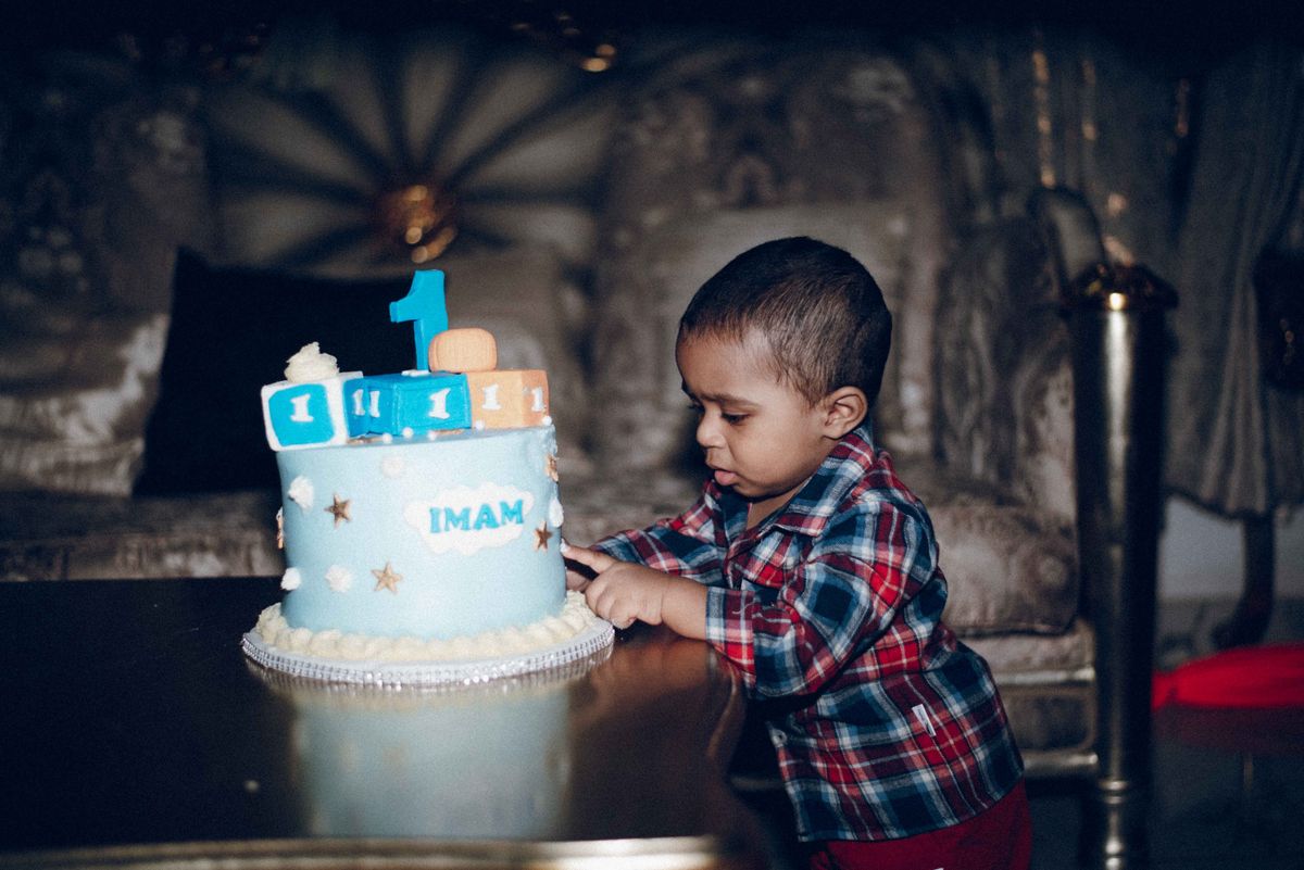 Toddler celebrating a first birthday smash cake with family