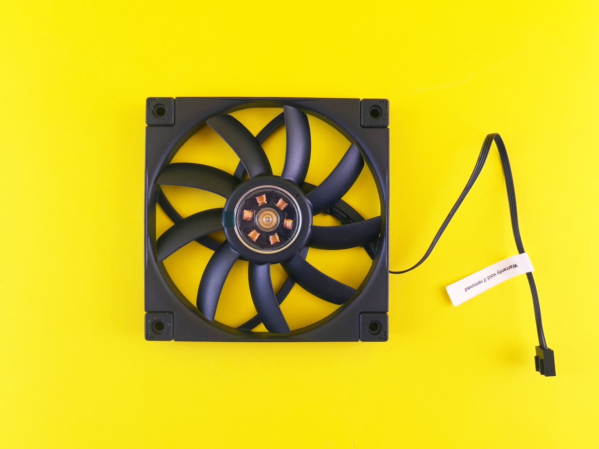 A black computer fan with a cable against a vibrant yellow backdrop, ideal for tech themes.