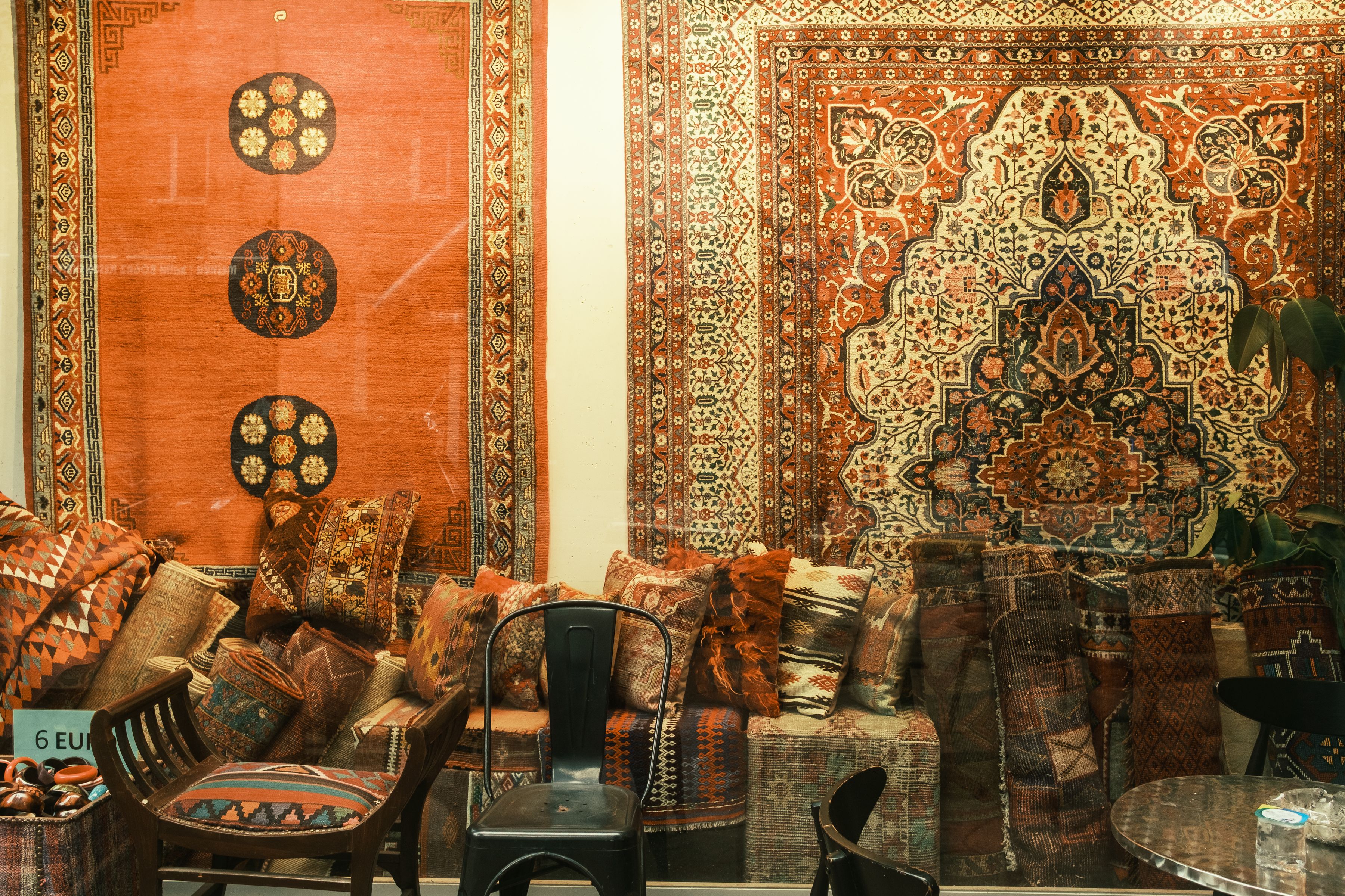 A vibrant display of traditional Persian rugs and patterned cushions in a cozy setting, perfect for decor inspiration.