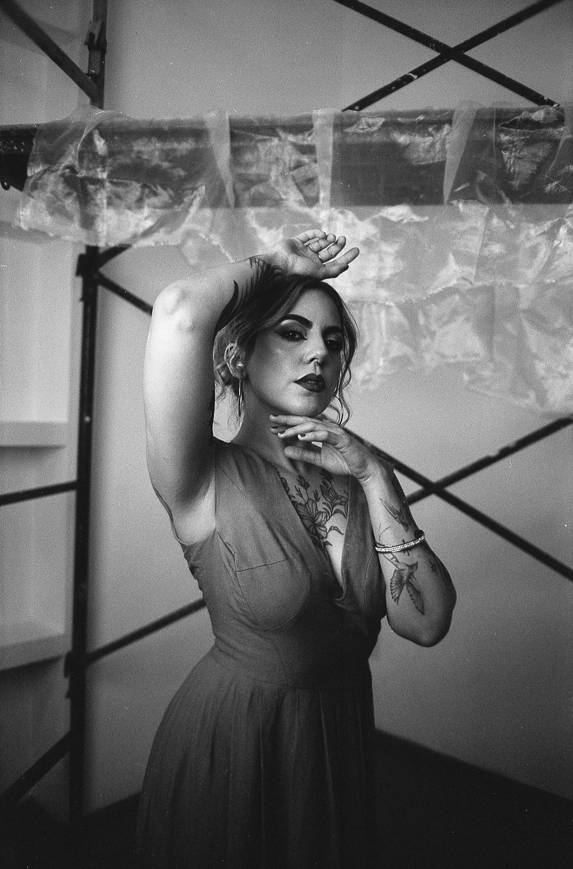 ingyenes Művészi fekete-fehér portré egy tetovált nőről, aki beltérben pózol. Stockfotó