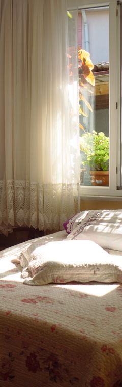 Sunlit guesthouse bedroom with lace curtains — photo by İrem Yılmaztürk on Pexels